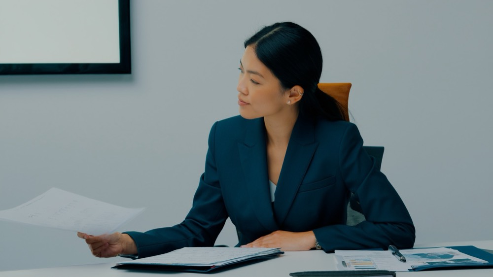 Real estate professional reviewing compliance documents at a desk with a laptop