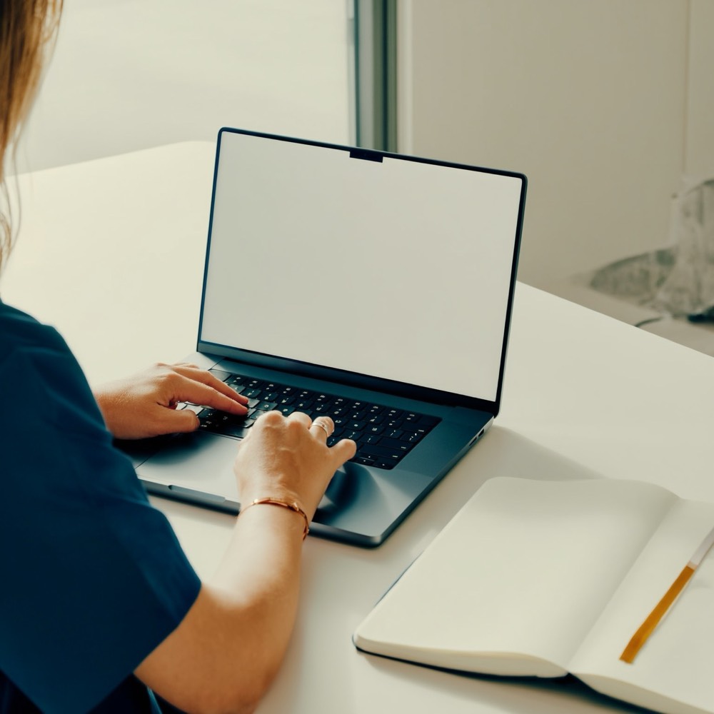 Close-up of hands working through course material on a laptop keyboard